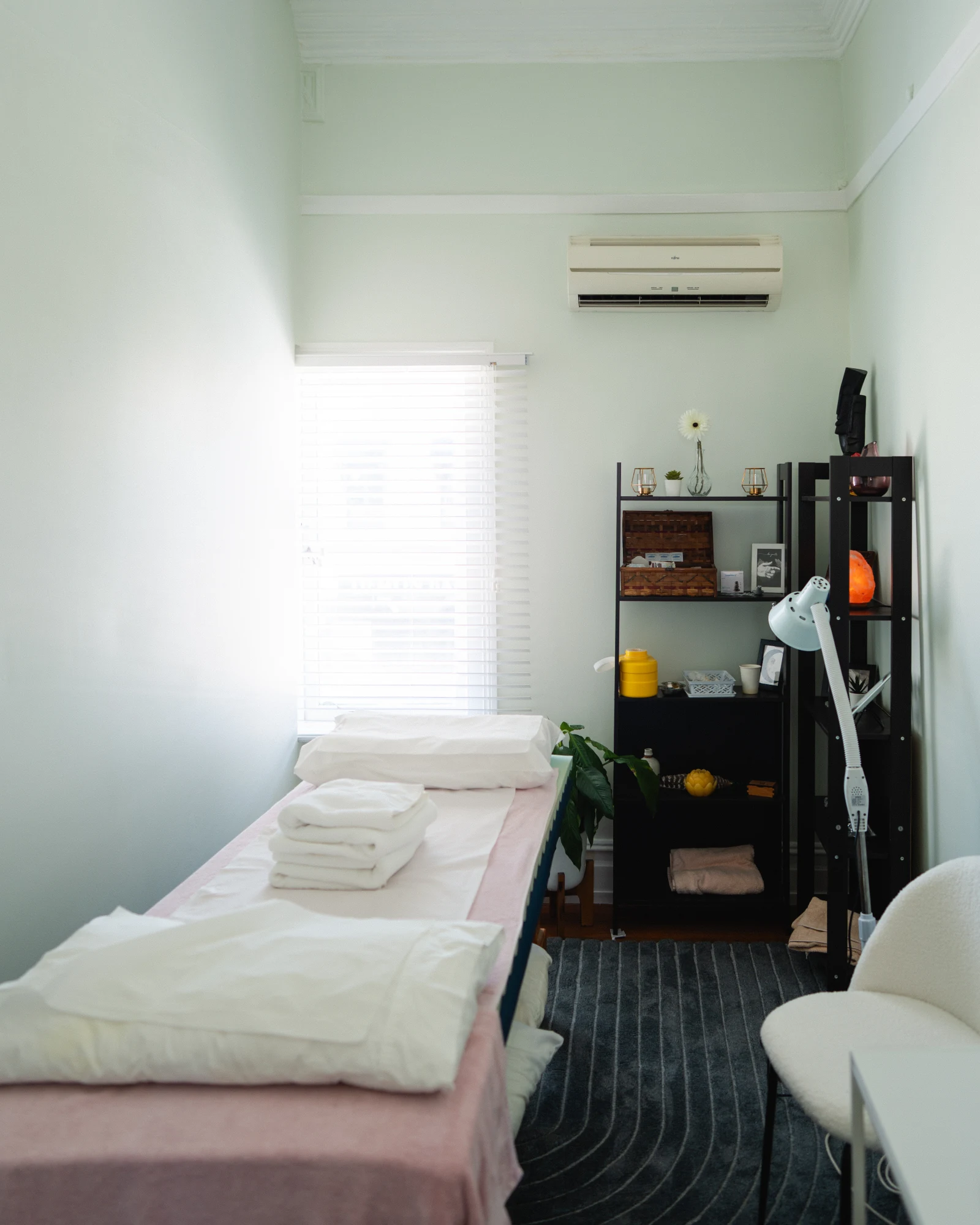 The Rozelle clinic treatment room with a prepared treatment table, folded towels, and soft daylight through venetian blinds